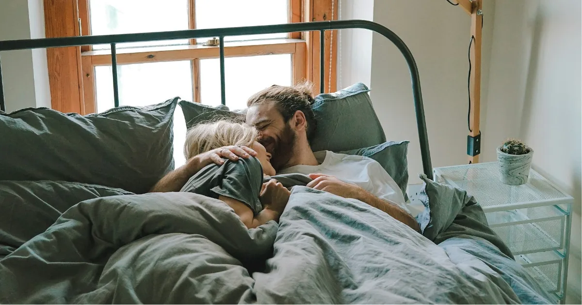 A Virgo man and his partner relaxing together in a dim, tidy bedroom