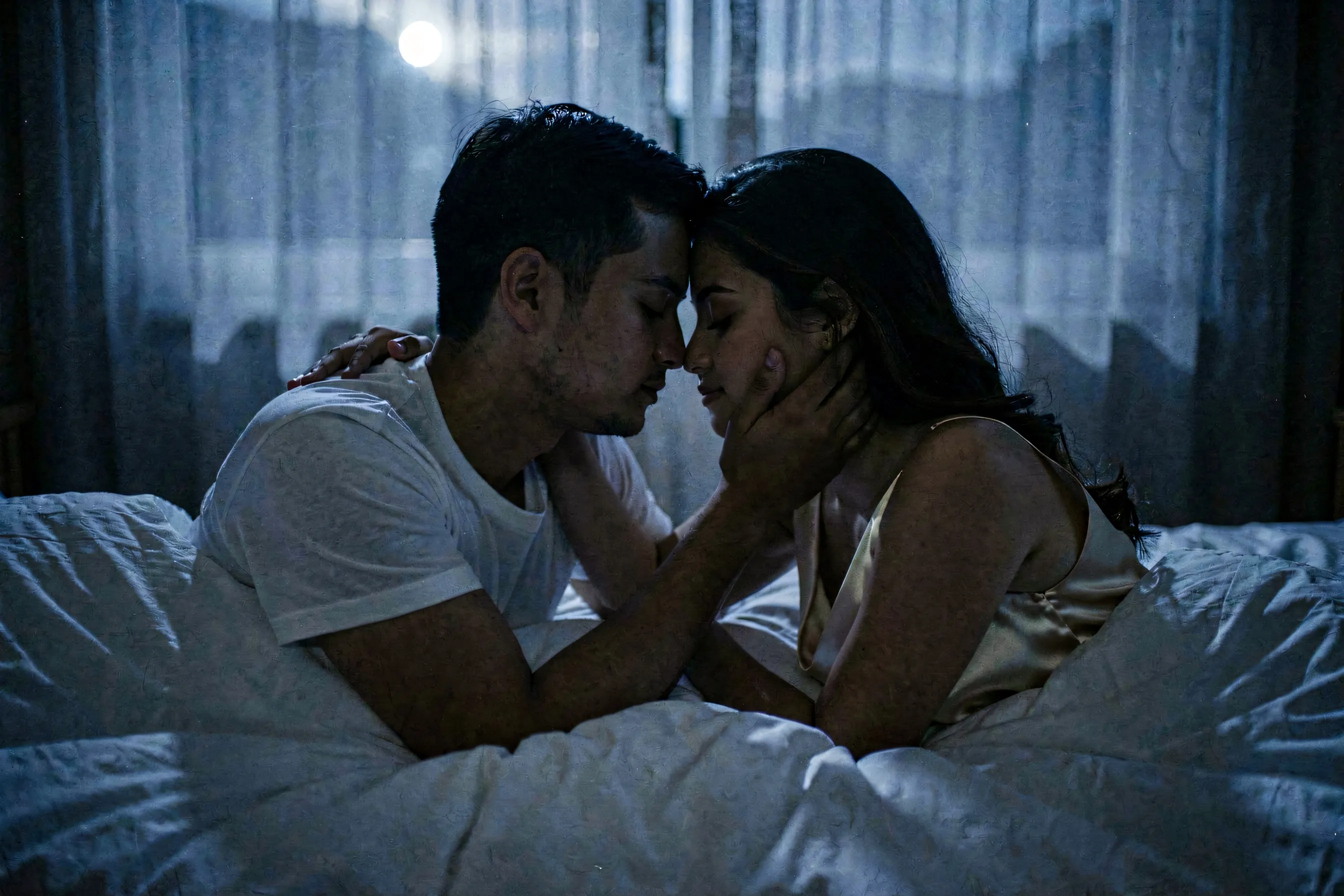 A couple lying close in a dim bedroom, faces inches apart, soft blue-grey light like moonlight
