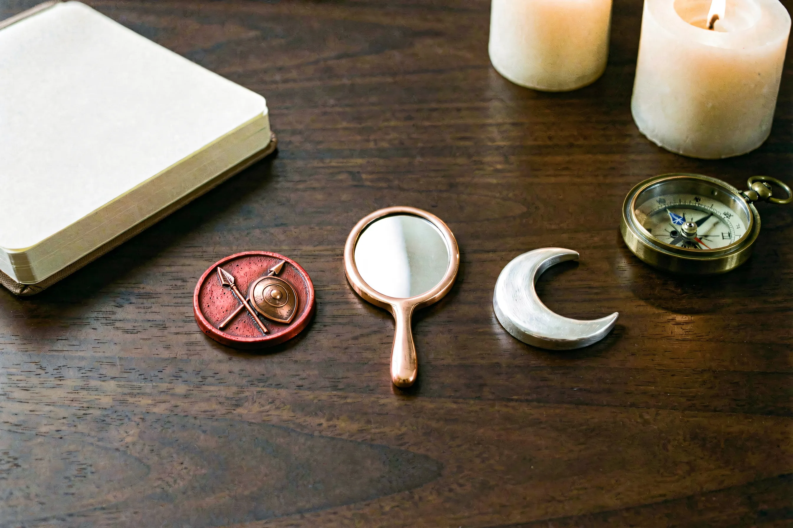 Three celestial tokens representing Mars, Venus, and the Moon on an astrologer’s desk