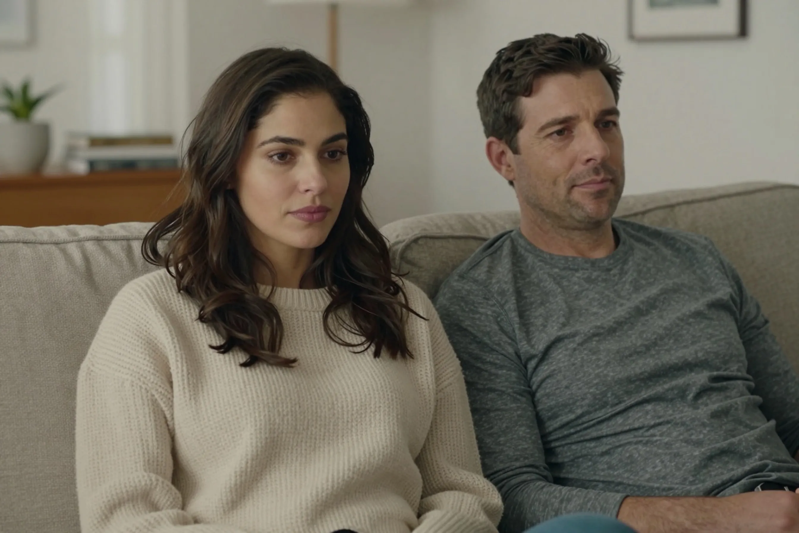 A woman and a man in their late 20s relaxing together on a sofa in a bright living room